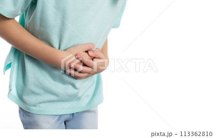 A child holds his stomach with his hands on a white background, close-up. Abdominal pain in children due to helminths, weight loss and poor health. Copy space for text, isolate 113362810