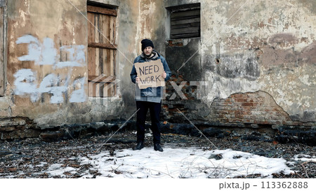 Homeless holds piece of cardboard with inscription Need Work. Refugee is looking for job. Male tramp in dirty clothes. Below poverty line. Bearded fugitive beggar. Immigrant. Drunkenness Homeless holds piece of cardboard with inscription Need Work. Refugee is looking for job. Male tramp in dirty clothes. Below poverty line. Bearded fugitive beggar. Immigrant. Drunkenness 113362888