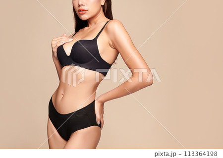 Confident beautiful young asian woman posing in black lingerie on beige background, Perfect body, 113364198
