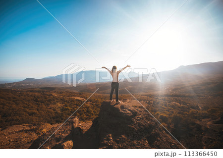 The girl looks at the mountains while facing the sun. High quality photo 113366450