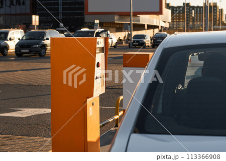 Car approaching to automatic barrier gates for supermarket parking lot. Security system for car park entry to shopping mall. Vehicle entrance with boom barriers and control tickets machine Car approaching to automatic barrier gates for supermarket parking lot. Security system for car park entry to shopping mall. Vehicle entrance with boom barriers and control tickets machine 113366908
