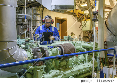 Marine Engineer in blue overall working in Engine room of ship. Work at sea. Motorman. Marine Engineer in blue overall working in Engine room of ship. Work at sea. Motorman. 113368947