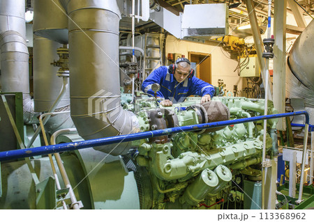 Marine Engineer in blue overall working in Engine room of ship. Work at sea. Motorman. Marine Engineer in blue overall working in Engine room of ship. Work at sea. Motorman. 113368962