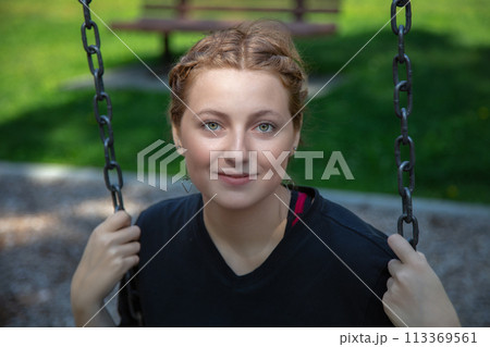 young woman sitting in a swing at the park playing outside happy enjoyment leisure 113369561