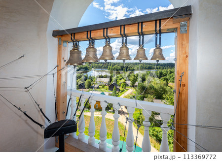 Orthodox bells on the church bell tower. Top view of the village and the lake Orthodox bells on the church bell tower. Top view of the village and the lake 113369772