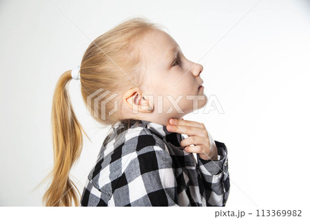 A blonde girl aged seven holds her sore throat with her hands. Sore throat and allergies in children. Inflammation of the lymph nodes, bacterium 113369982