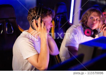 Gamers of team puts on headsets at PC computer club, cyber sport tournament. E-sport championship. 5 players in headphones playing video game. Multiplayer online battle, tactical first-person shooter Gamers of team puts on headsets at PC computer club, cyber sport tournament. E-sport championship. 5 players in headphones playing video game. Multiplayer online battle, tactical first-person shooter 113370096