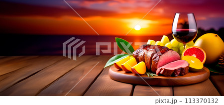 Meat with tropical fruits and glass of red wine against evening setting sun. Caribbean roast. Banner with space for text 113370132