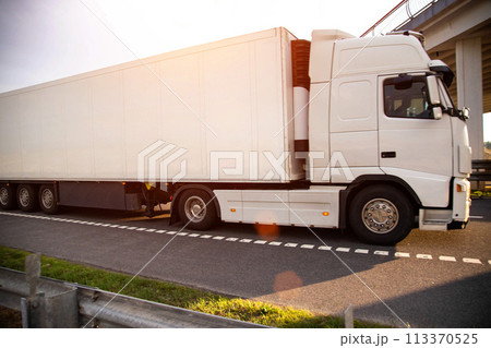 A white modern truck with an isothermal refrigerated semi-trailer transports perishable products in a trailer with a constant temperature regime. Transportation of seafood, fruits and meat. Copy space 113370525