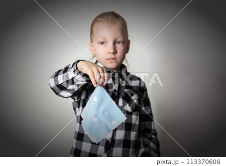 a sad girl aged seven years old holds a handkerchief in her hand against the background of a plaid shirt. Concept of runny nose and nasal congestion in children. Chronic rhinitis and sinusitis. Acute a sad girl aged seven years old holds a handkerchief in her hand against the background of a plaid shirt. Concept of runny nose and nasal congestion in children. Chronic rhinitis and sinusitis. Acute 113370608