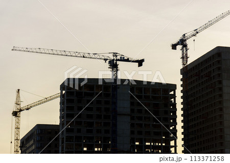 Construction cranes on top of a building under construction. The cranes are engaged in the construction work of the building. 113371258