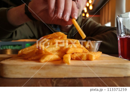 Close-Up of French Fries on Cutting Board, selective focus 113371259