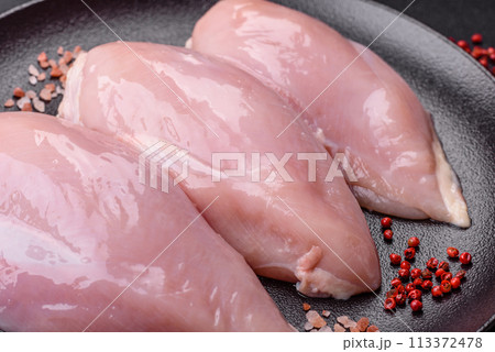 Fresh chicken fillet on a dark concrete table with spices and herbs Fresh chicken fillet on a dark concrete table with spices and herbs 113372478