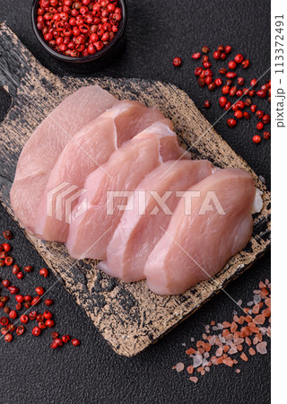 Slices of raw chicken or turkey fillet with salt, spices and herbs Slices of raw chicken or turkey fillet with salt, spices and herbs 113372491