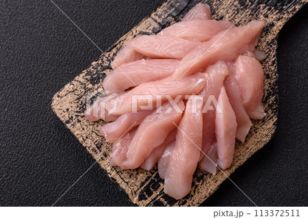 Slices of raw chicken or turkey fillet with salt, spices and herbs Slices of raw chicken or turkey fillet with salt, spices and herbs 113372511