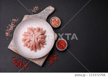 Slices of raw chicken or turkey fillet with salt, spices and herbs 113372708