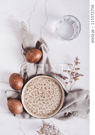 Naturally colored Easter eggs, plate, cutlery and glass of water on the table top and vertical view 113372756