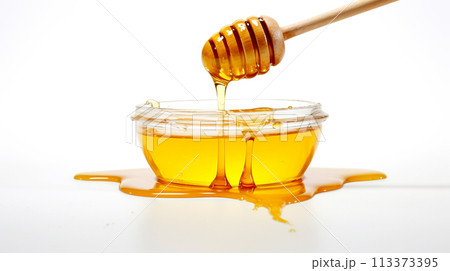 Wooden Honey Dipper Dipped in Jar of Golden Honey on White Background with Honey Splash Nearby 113373395