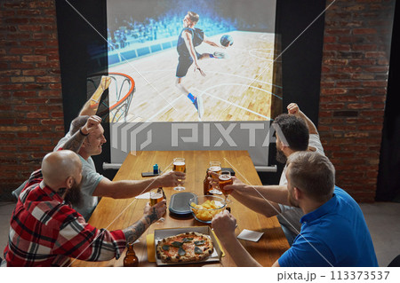 Men, sports enthusiasts gathering to watching online basketball match translation, cheering on their favorite team 113373537
