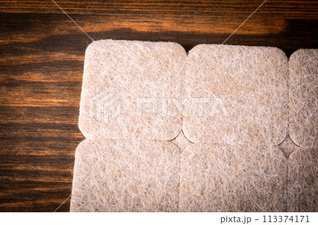Furniture Protection Felt on a dark wood texture background Furniture Protection Felt on a dark wood texture background 113374171