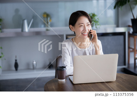 綺麗な会社、オフィスやコワーキングスペースで仕事をしながら電話で話しをする美しいミドル女性 綺麗な会社、オフィスやコワーキングスペースで仕事をしながら電話で話しをする美しいミドル女性 113375356