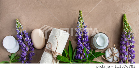 Natural organic cosmetics and lupine flowers on craft paper background. Natural organic cosmetics and lupine flowers on craft paper background. 113376703