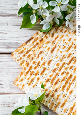Happy Passover flatlay. Jewish matzo bread and flowers on white wooden background. Happy Passover flatlay. Jewish matzo bread and flowers on white wooden background. 113376713