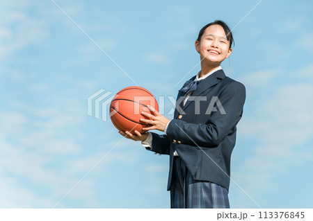 青空の中でバスケットボールを持つ女子中学生・女子高生（部活・スポーツ・運動部・バスケ部） 113376845
