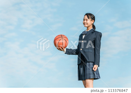 青空の中でバスケットボールを持つ女子中学生・女子高生（部活・スポーツ・運動部・バスケ部） 113376847