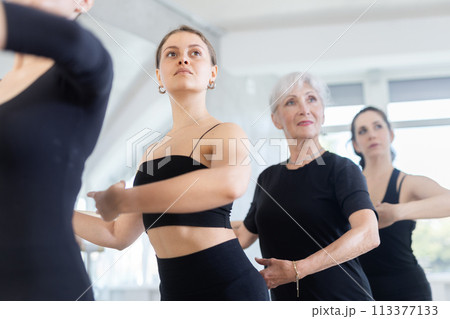 Group of women stand in position at ballet barre Group of women stand in position at ballet barre 113377133