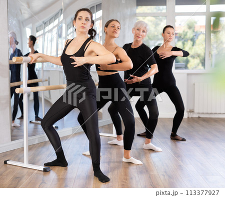 Girls in ballet class perform composition with grand plie with participation of mature female mentor 113377927