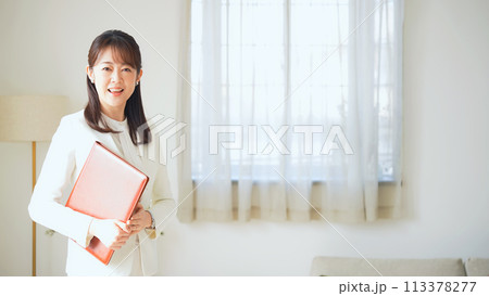 カジュアルな部屋でファイルを持って立つミドル女性 113378277