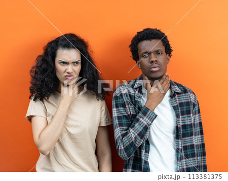 Couple Feeling Unwell With Sore Throats Against Orange Background Couple Feeling Unwell With Sore Throats Against Orange Background 113381375