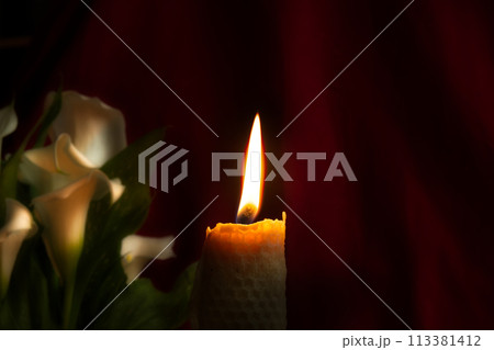Burning wax candle and white lily flowers in darkness Burning wax candle and white lily flowers in darkness 113381412