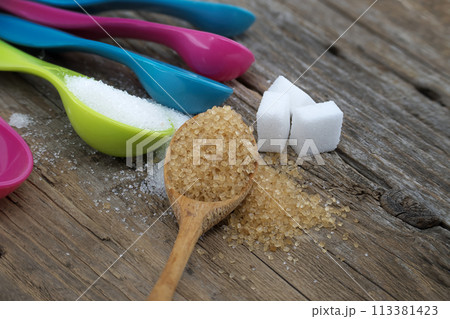 Brown cane sugar and white sugar in measuring spoons Brown cane sugar and white sugar in measuring spoons 113381423