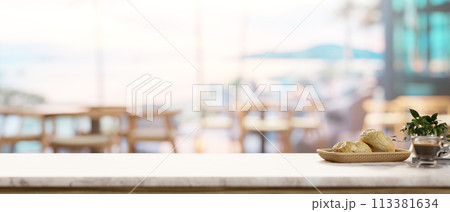 A space on a white marble tabletop, with a blurred background featuring a contemporary coffee shop. 113381634