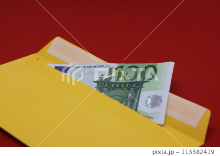 Banknotes in a yellow envelope on a red background. Bribery concept. Salary in envelopes, fraud. Banknotes in a yellow envelope on a red background. Bribery concept. Salary in envelopes, fraud. 113382419