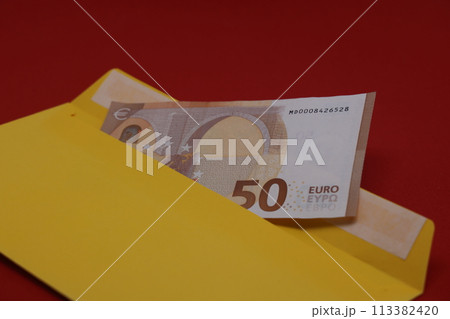 Banknotes in a yellow envelope on a red background. Bribery concept. Salary in envelopes, fraud. Banknotes in a yellow envelope on a red background. Bribery concept. Salary in envelopes, fraud. 113382420