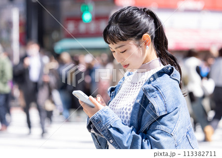 ストリートスナップ　街中でスマホを見ている若い女性 113382711