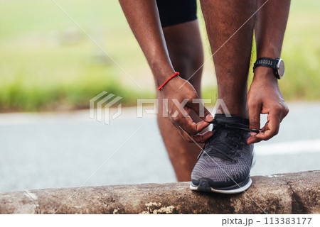 Close up Asian sport runner black man wear watch stand step on the footpath trying shoelace running shoes getting ready for jogging and run outdoor street health park, healthy exercise workout concept 113383177