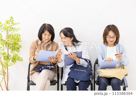 待合室でクリップボードに記入する女性 113386304