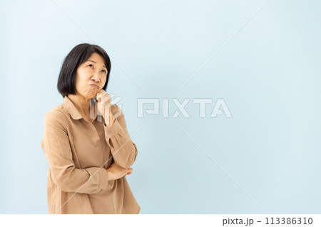 悩むシニア女性　ブルーバック 113386310