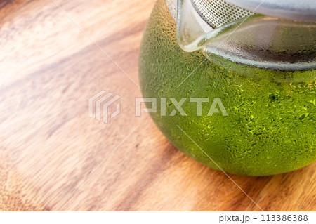 汗をかいたガラスのポットに入った冷たい水出し緑茶 113386388