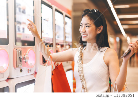 Young adult asian woman playing crane game indoors department store. Young adult asian woman playing crane game indoors department store. 113388051