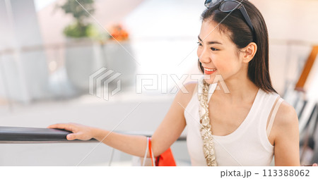 Asian woman standing on escalator with shopping bags in department store city lifestyles Asian woman standing on escalator with shopping bags in department store city lifestyles 113388062