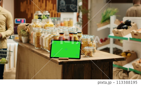 Greenscreen display shown on tablet at neighborhood grocery store, support low carbon footprint and eco friendly farming. Gadget with blank copyspace layout next to bulk items in jars. Camera 1. Greenscreen display shown on tablet at neighborhood grocery store, support low carbon footprint and eco friendly farming. Gadget with blank copyspace layout next to bulk items in jars. Camera 1. 113388195