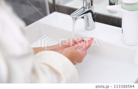 Woman washing her hands under water from tap in bathroom closeup Woman washing her hands under water from tap in bathroom closeup 113388564