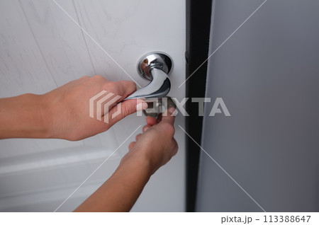 Door lock is opened by woman hand closeup Door lock is opened by woman hand closeup 113388647