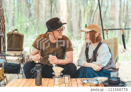 キャンプ場でコーヒーミルを使ってコーヒーを淹れる夫婦キャンパー・カップル・男女 113388778