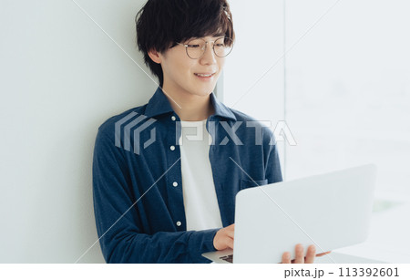 パソコンを操作するメガネの若い男性 パソコンを操作するメガネの若い男性 113392601